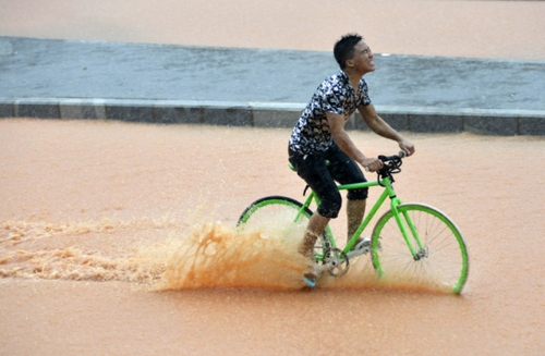 5月11日，一名行人在深圳街頭冒雨騎行。