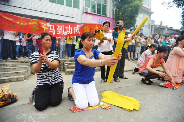 　送考家長(zhǎng)和村民燒紙跪拜。