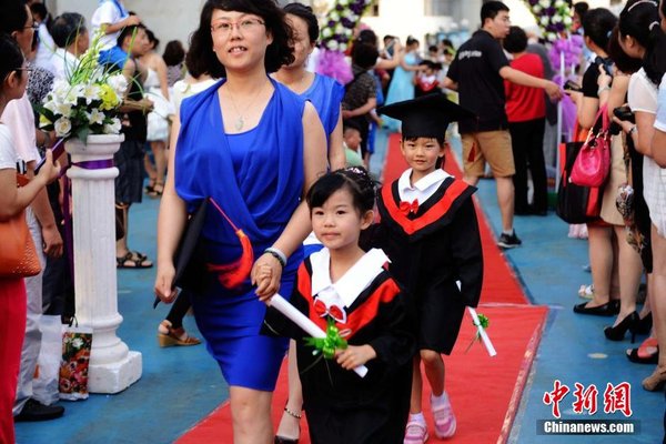 6月28日，山東青島開發(fā)區(qū)第一幼兒園怡和嘉園分園2014級大班舉行畢業(yè)典禮，全體畢業(yè)生身著學(xué)士服在盛裝父母的陪同下，依次走過紅毯，在畢業(yè)榜上鄭重簽下自己的名字，其氣勢不輸當(dāng)紅影星紅毯秀。中新社發(fā) 俞方平 攝 圖片來源：CNSPHOTO