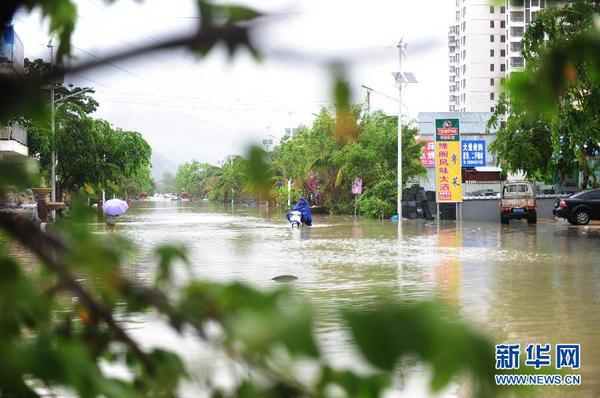 6月23日，在海南省三亞市，人們?cè)诜e水路段涉水前行。今年第8號(hào)臺(tái)風(fēng)“鯨魚”已于6月22日18時(shí)50分左右在海南省萬(wàn)寧市沿海登陸，臺(tái)風(fēng)給三亞帶來(lái)了強(qiáng)風(fēng)降雨天氣，影響市民正常出行。新華社發(fā)（沙曉峰 攝）