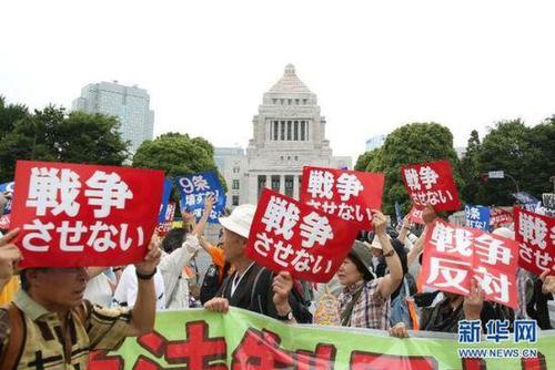 2015年7月14日，日本民眾在國會外集會，手舉標(biāo)語牌，高喊口號示威，抗議新安保法