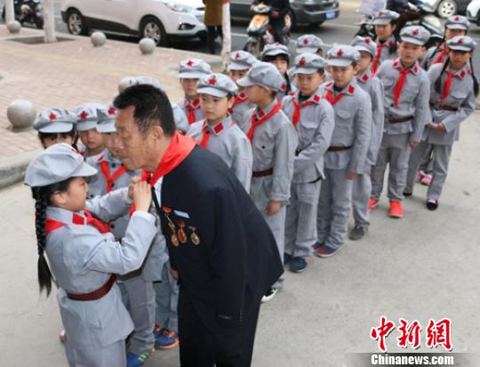 受谷殿明血雷鋒事跡的感染，雷鋒小標(biāo)兵為這位“活雷鋒”爺爺系上紅領(lǐng)巾?！」鶊@ 攝