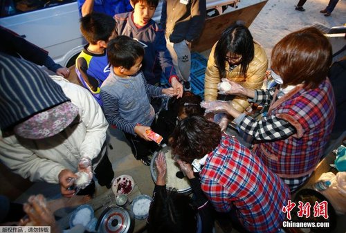 當?shù)貢r間4月17日，志愿者在公園的空地上制作飯團發(fā)放給小朋友。