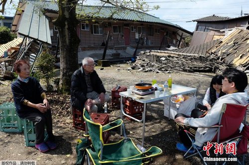 當(dāng)?shù)貢r間4月17日，日本熊本縣震后見聞。一家人圍坐在簡易桌旁吃飯，周圍都是倒塌的房屋。