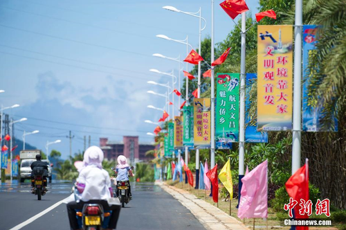 6月24日，海南省文昌市龍樓鎮(zhèn)街道兩側(cè)五星紅旗迎風(fēng)飄揚(yáng)，火箭“首發(fā)”宣傳廣告隨處可見。長征七號運(yùn)載火箭發(fā)射日期臨近，中國首個濱海航天發(fā)射中心——文昌航天發(fā)射場所在地海南省文昌市龍樓鎮(zhèn)將迎來“首發(fā)”，中國的“卡納維拉爾角”正揭開神秘面紗。中新社記者 駱云飛 攝