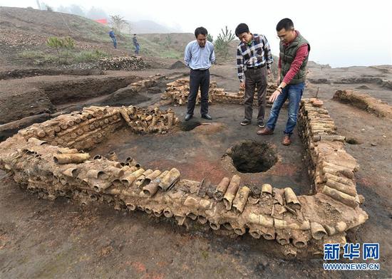 在桐木嶺礦冶遺址，考古人員查看用廢棄坩堝壘筑的房屋遺址（11月18日攝）。