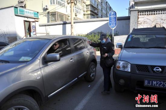 今年元月起，北京全市3000多名路側(cè)停車管理員上崗證更換，新上崗證標(biāo)有二維碼，市民用手機掃描即可看到管理員的照片、姓名、所在公司、監(jiān)督電話等詳細信息。若冒用或偽造，掃描出來的信息將與實際不符，一旦遇到假收費員，市民有權(quán)拒絕交費。圖為停車場管理員張大姐為車主指揮倒車。<a target='_blank' href='http://www.chinanews.com/' >中新網(wǎng)</a>記者 金碩 攝