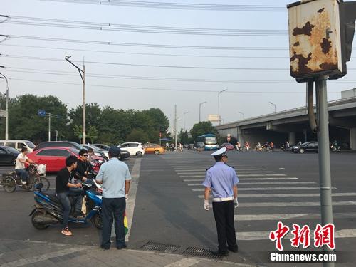 6月21日上午，北京仰山橋下十字路口，執(zhí)勤人員要求非機(jī)動車停在停止線后。湯琪 攝