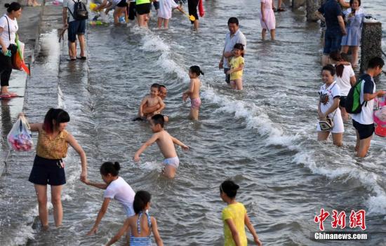 7月4日傍晚，市民們帶著小孩在海邊戲水消暑。連日來，受副熱帶高壓影響廈門地區(qū)持續(xù)高溫。 張斌 攝