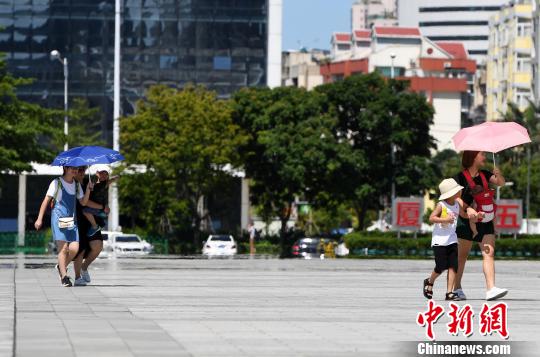 7月13日，廈門(mén)市民行走在熱浪滾滾的路面上。　張斌 攝