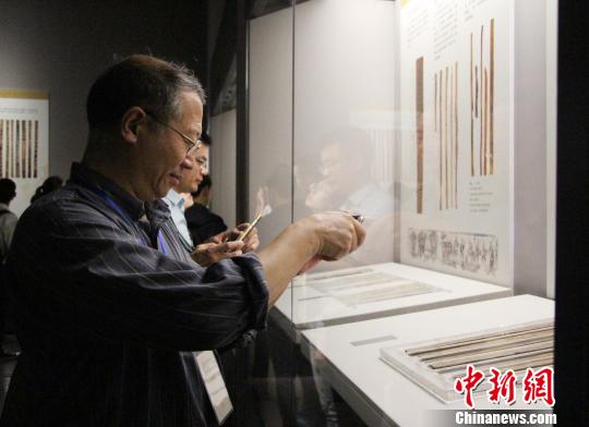 圖為參展觀眾在中國簡帛文化展上觀看和拍攝簡帛文物?！≮w曉　攝