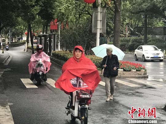 11日，南京迎來降溫降雨。圖為市民披上雨衣出行?！铑伌?攝