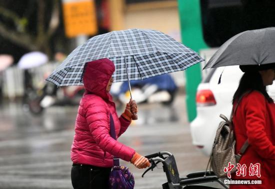 資料圖：昆明市區(qū)里身著羽絨服冒雨趕路的民眾。 中新社記者 李進(jìn)紅 攝