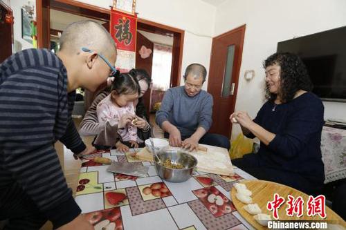 圖為彭秀芳“一家四口”包餃子。(抱著玲玲的是福利院工作人員) 胡貴龍 攝