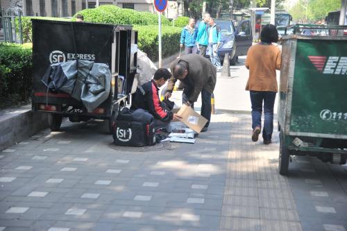 圖為快遞小哥在路邊配送快遞。呂春榮 攝