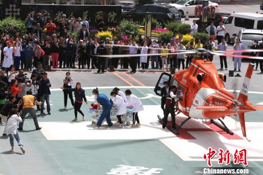 5月23日，遼寧省人民醫(yī)院完成中國東北首例異地航空醫(yī)療轉(zhuǎn)運任務。圖為急救人員立即將患者抬上急救床?！≈烀饔?攝