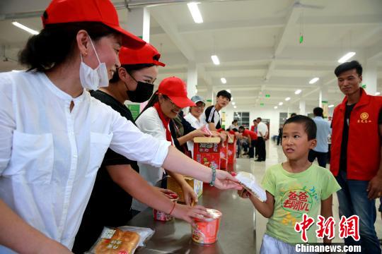 8月24日，志愿者在濰坊壽光市營(yíng)里鎮(zhèn)第二初級(jí)中學(xué)安置點(diǎn)為災(zāi)民發(fā)放救援物資。　梁犇 攝