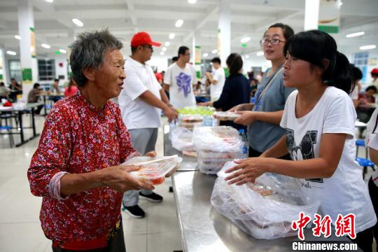 8月24日，志愿者在濰坊壽光市營(yíng)里鎮(zhèn)第二初級(jí)中學(xué)安置點(diǎn)為災(zāi)民發(fā)放救援物資。　梁犇 攝