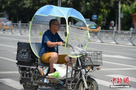 資料圖：男子在電動(dòng)車上撐起遮陽棚。<a target='_blank' href='http://www.chinanews.com/'>中新社</a>記者 劉文華 攝