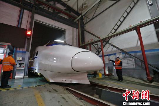 一列動車組駛?cè)胲噹?，機械師位列兩邊檢查車體外觀?！《〔?攝