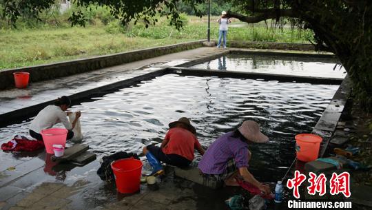 幾名婦女在“雅蔡冷泉”旁一邊聊天一邊洗著衣物。　符宇群 攝