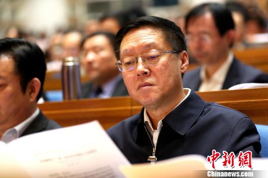 圖為與會政協(xié)委員在現(xiàn)場閱讀會議文件。　梁犇 攝