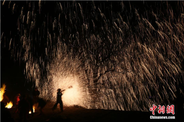 該村“打樹花”的習(xí)俗已延續(xù)了近600年，村民將生鐵融成鐵水后，再用特制的木板將鐵水擊打至樹上，頓時(shí)綻放出萬點(diǎn)“鐵花”。中新社記者 陳昊 攝