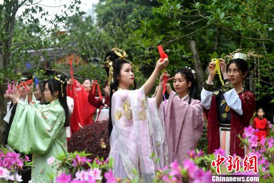 福建漢服少女將將寫(xiě)有對(duì)春日祝福的彩帶系在百花枝頭，共同送上美好的祝愿?！蚊?攝