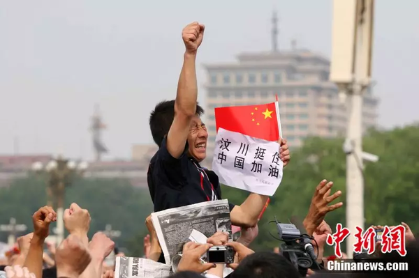 2008年5月19日，北京天安門廣場上的民眾為地震遇難者默哀，一位來自四川的男子高舉右手為家鄉(xiāng)加油。中新社記者 富田 攝