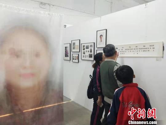 在第19屆中國平遙國際攝影大展柴油機(jī)展區(qū)的一角，一張大幅的人像彩畫吸引來往游客駐足拍照?！钆迮?攝