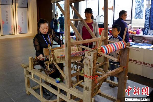 非遺傳承人向觀眾展示織布機(jī)的使用方法。　張強(qiáng) 攝