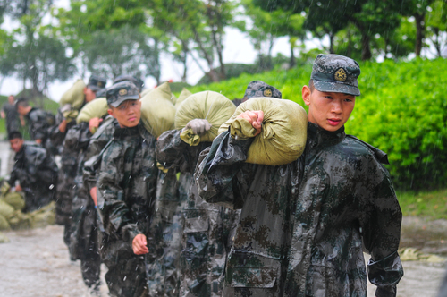 圖為在安徽合肥巢湖任務(wù)區(qū)官兵在暴雨中扛運(yùn)沙袋，加固堤壩。（王文洲 攝）